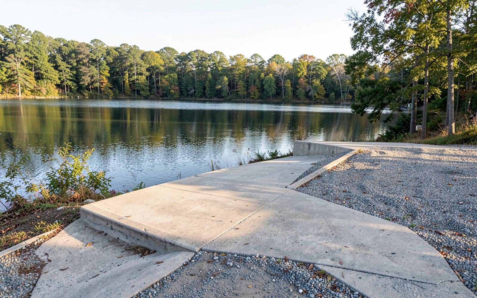 A quiet public concrete boat ramp sloping into Mountain Island Lake with gravel parking