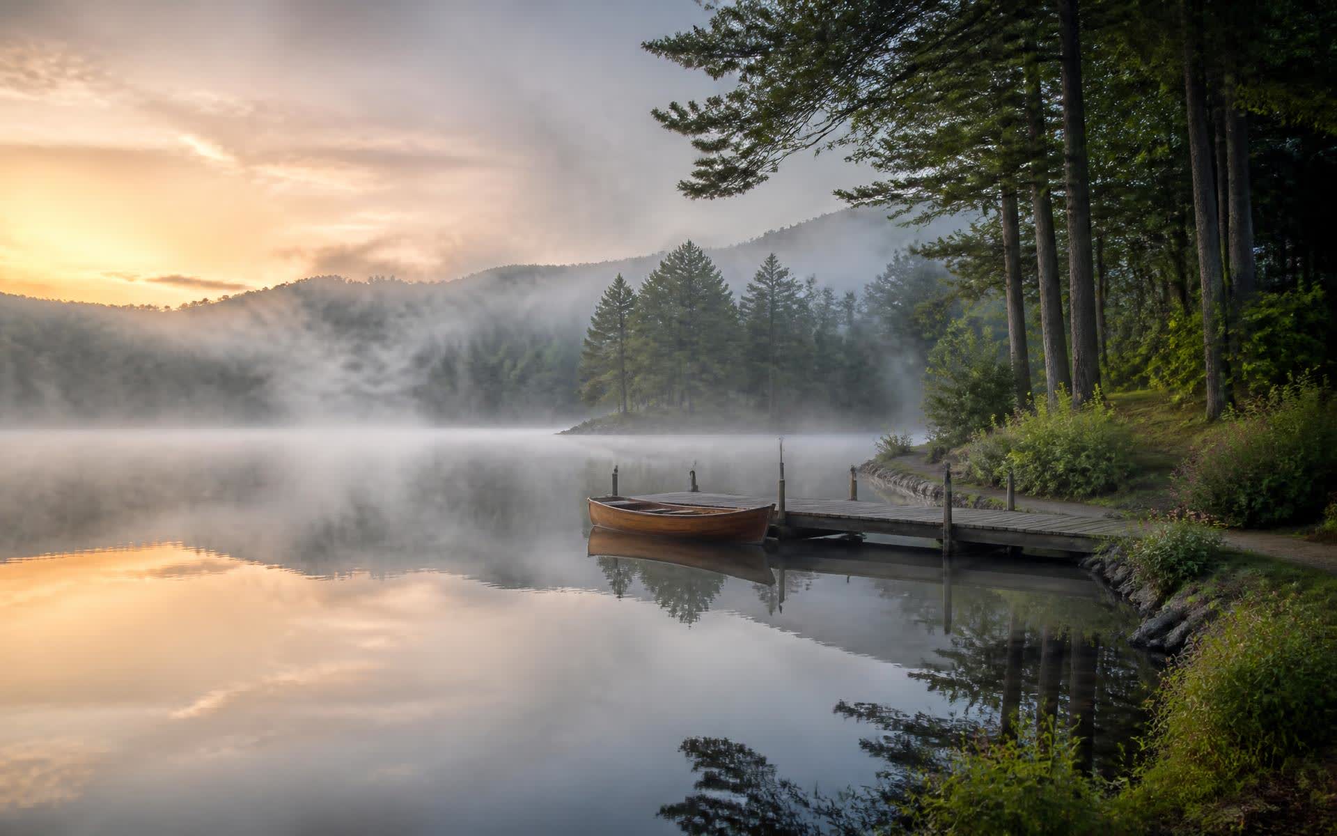 Wooden boat tied to a dock in morning mist on Mountain Island Lake