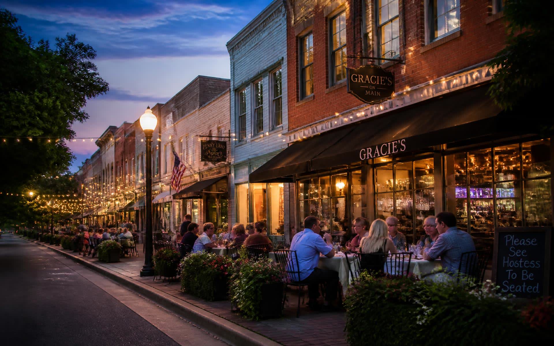 Small-town main street at twilight with outdoor restaurant seating