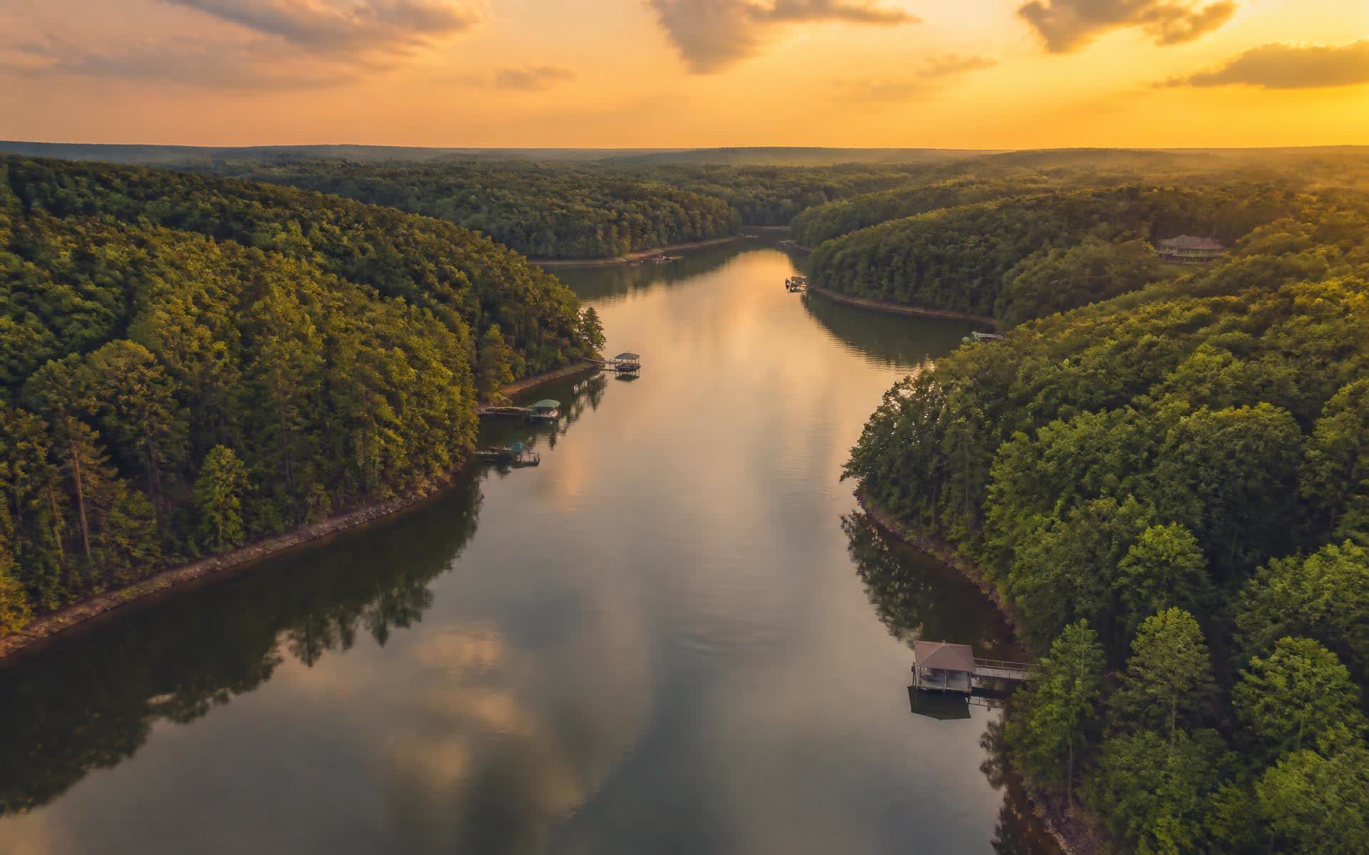 Aerial view of Mountain Island Lake at golden hour, forested shoreline and scattered private docks